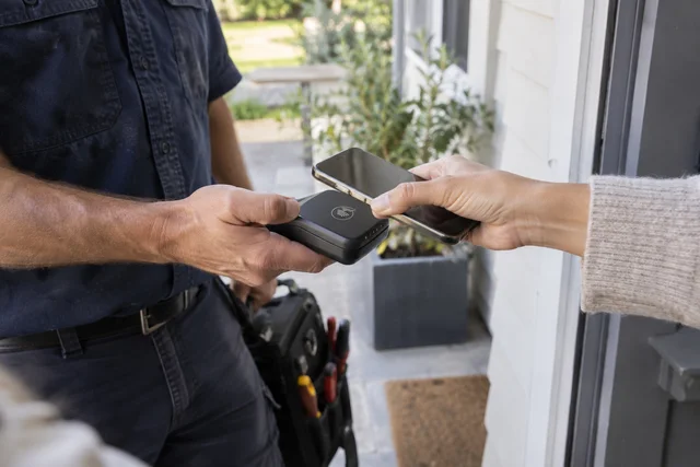 A home service professional taking a contactless payment at a customer’s door