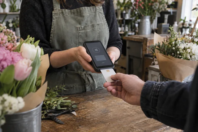 A florist accepting a card payment on a modern touchscreen terminal